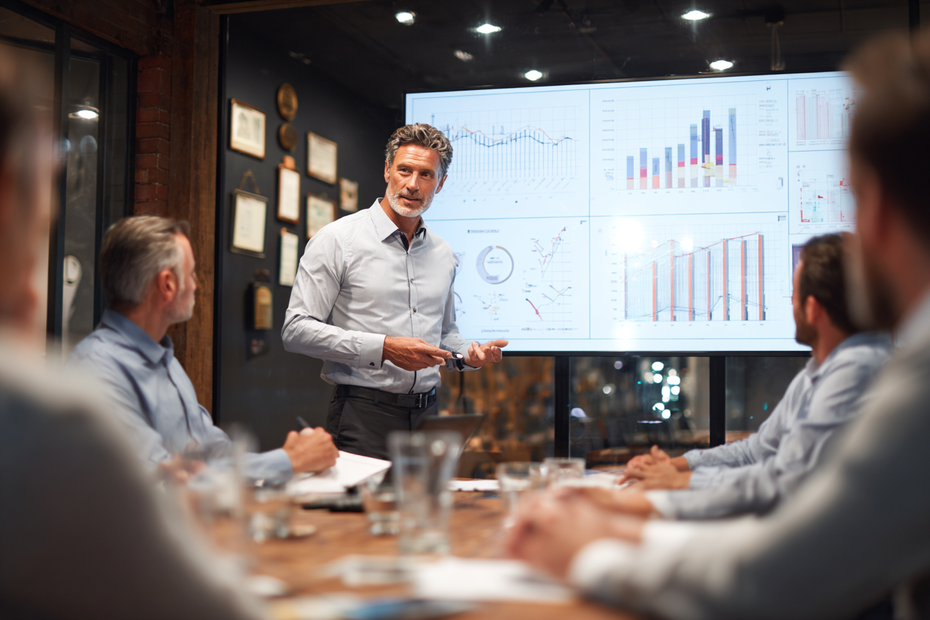 captive insurance manager presenting risk management data to manufacturing and construction company executives in corporate boardroom
